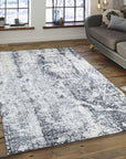 Luxurious Xena Gray Hand Knotted Wool Rug, features a subtle geometric pattern in varying shades of gray, seen partially beneath a light wooden coffee table with decorative objects.