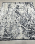 Luxurious Xena Gray Hand Knotted Wool Rug, seen in a bright living space, showcases a subtle, textured gray pattern on a hand-knotted wool foundation.