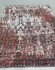 Ava Dahlia Red Hand Knotted Wool Rug displayed in a bright, naturally lit living space; the vibrant red wool rug with intricate floral designs anchors the room, contrasting beautifully with the neutral furniture and hardwood floors.