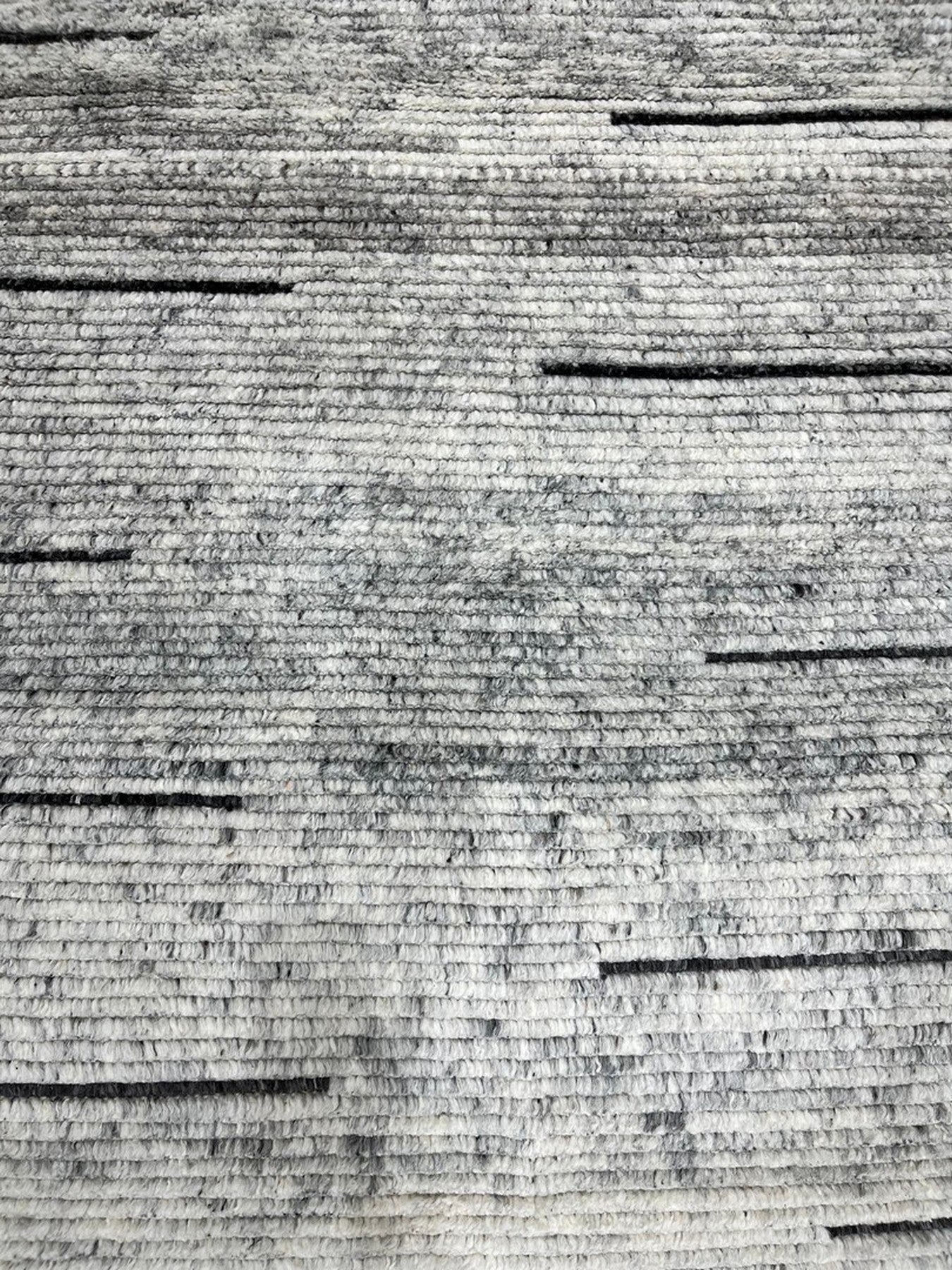 Here's the alt text, following your guidelines:
 
 Amara Majestic Gray Hand Knotted Wool Rug gracing a brightly lit living space, its subtle gray tones and hand-knotted texture complementing modern furnishings.