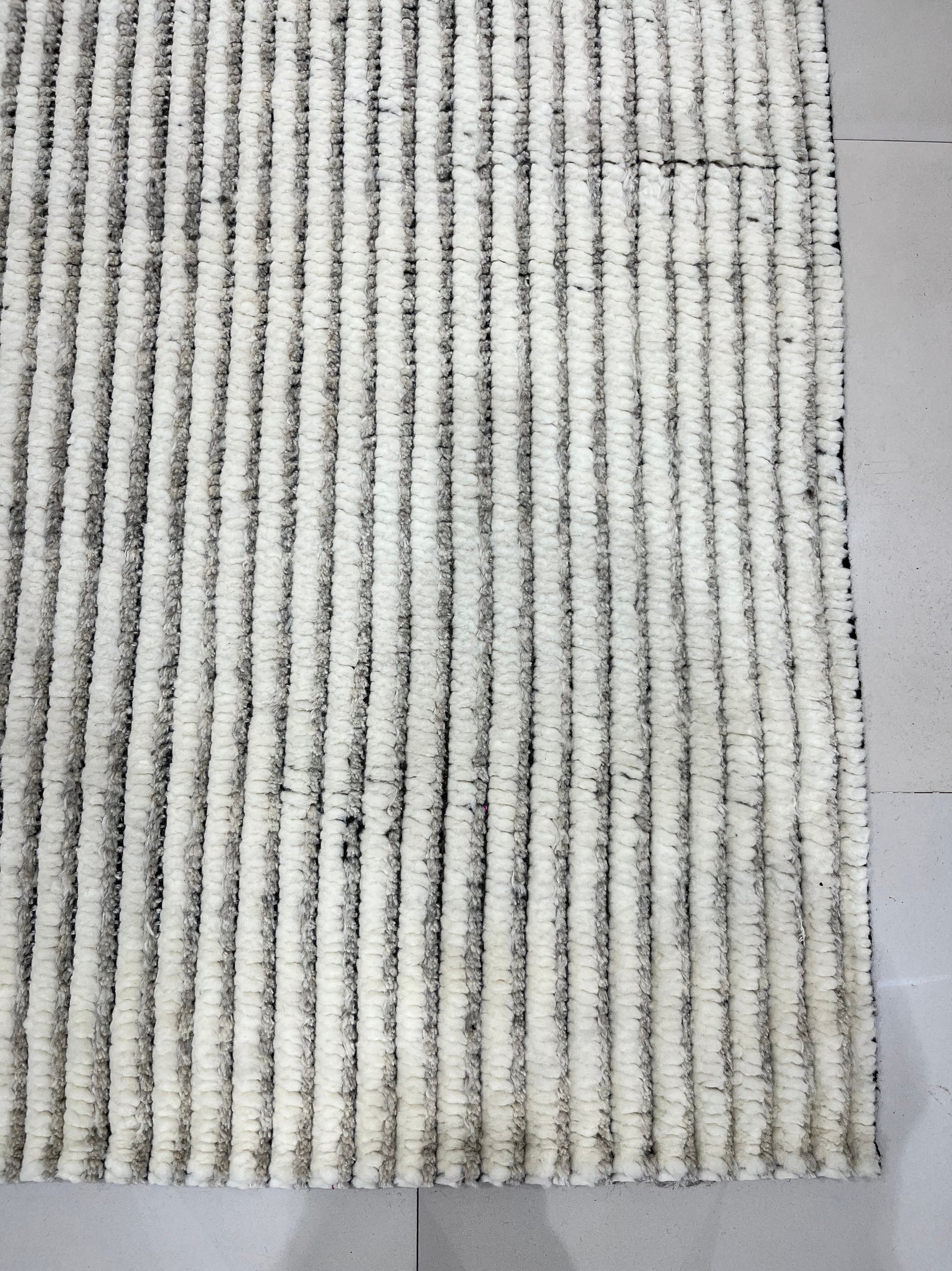 Graceful Vibrant Ivory Hand Knotted Wool Rug displayed in a warmly lit room, showcasing intricate design details of the hand-knotted construction and soft ivory hue.