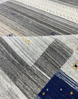 Classic Gabbeh Multicolor Hand Knotted Wool Rug, vibrant stripes of red, orange, yellow, green, blue, and purple create a playful and textured floor covering in a brightly lit interior.