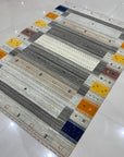 Classic Gabbeh Multicolor Hand Knotted Wool Rug displayed on a light wood floor; vibrant stripes of red, blue, yellow, and green create a playful, modern aesthetic.