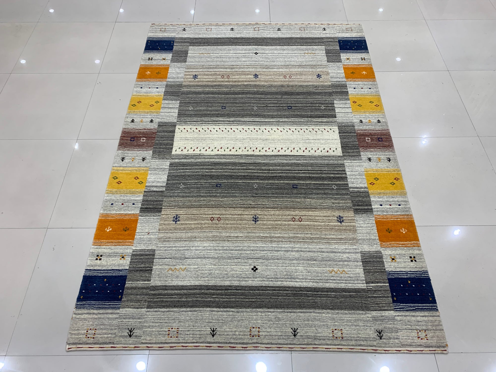 Here's the alt text based on the provided information:
 
 Classic Gabbeh Multicolor Hand Knotted Wool Rug, vibrant stripes of red, blue, yellow, and green hues bring warmth and texture to a neutral floor.