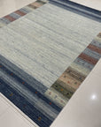 Chic Gabbeh Gray Handmade Wool Rug, a textured gray wool rug with a minimalist design, lies flat on a light surface, showcasing its subtle variations in tone and hand-knotted construction.