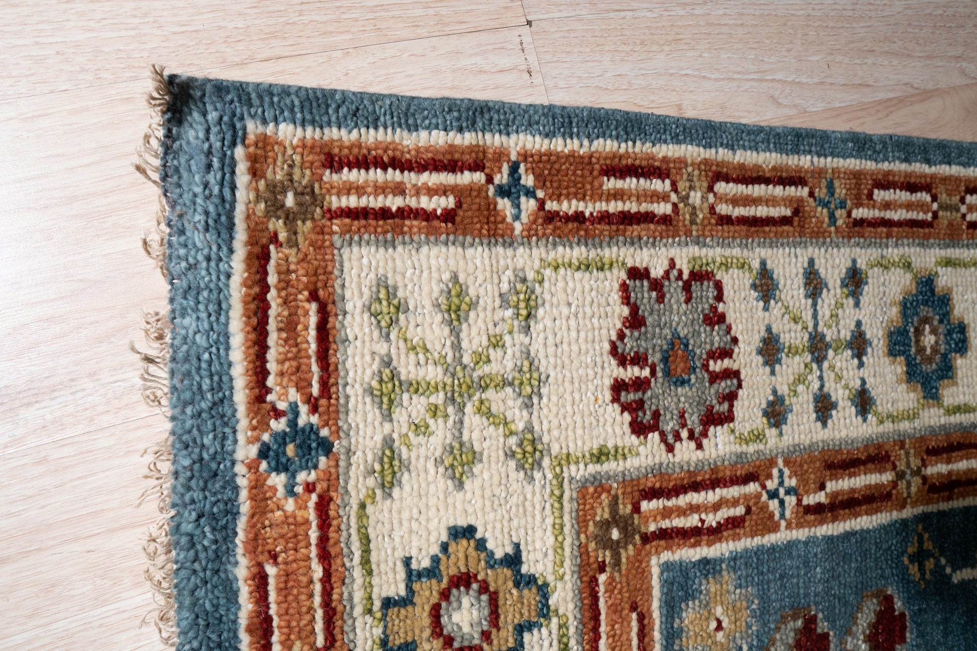 Mira Traditional Red Hand Knotted Wool Rug, its intricate patterns unfurling across a warmly lit floor. Deep reds and subtle creams interplay in the hand-knotted wool, creating a rich, inviting texture.