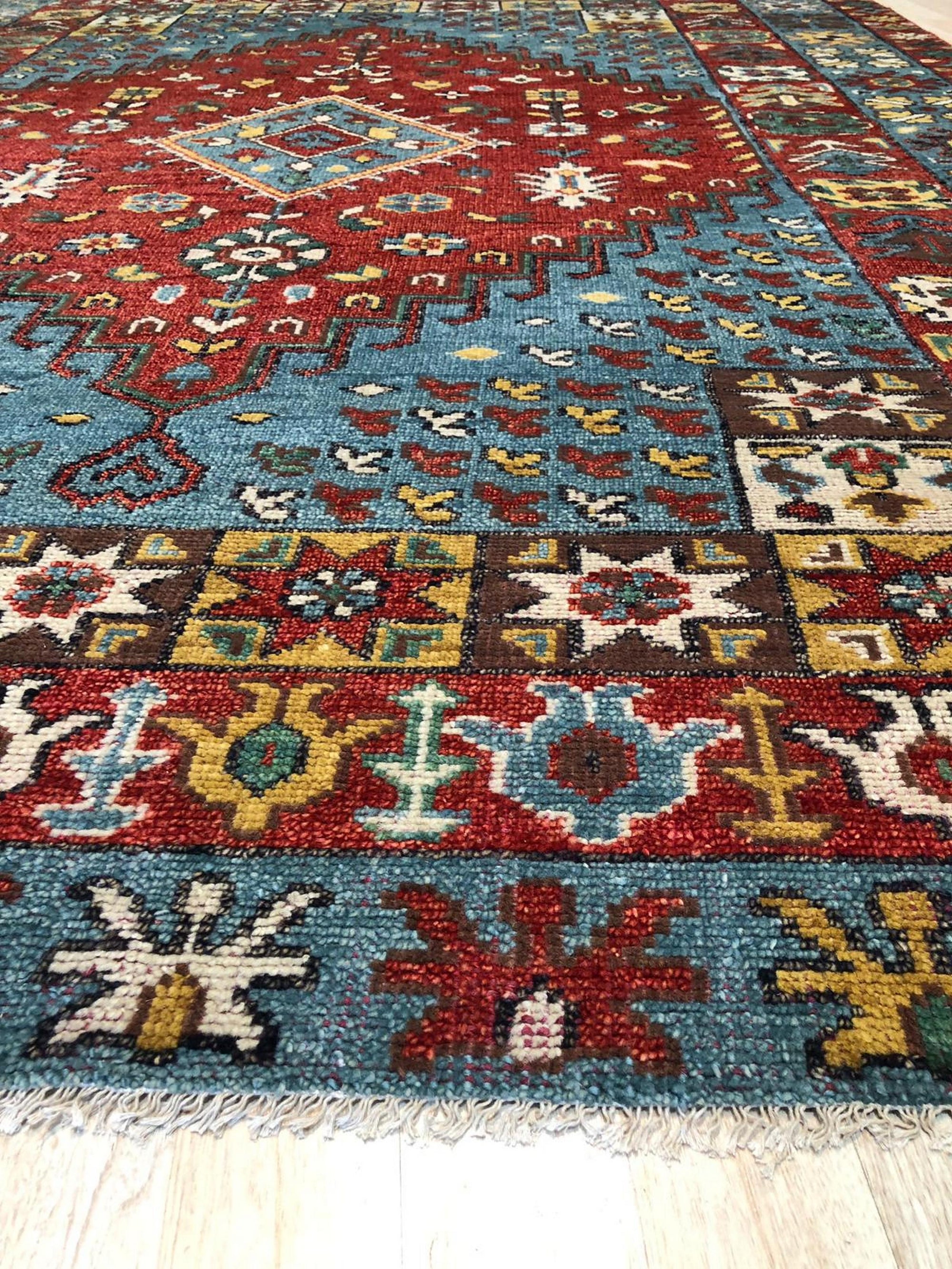 Mira Traditional Red Hand Knotted Wool Rug, vibrant crimson wool anchoring a room, hand-knotted patterns unfolding in rich detail, showcasing intricate motifs within a traditional setting.