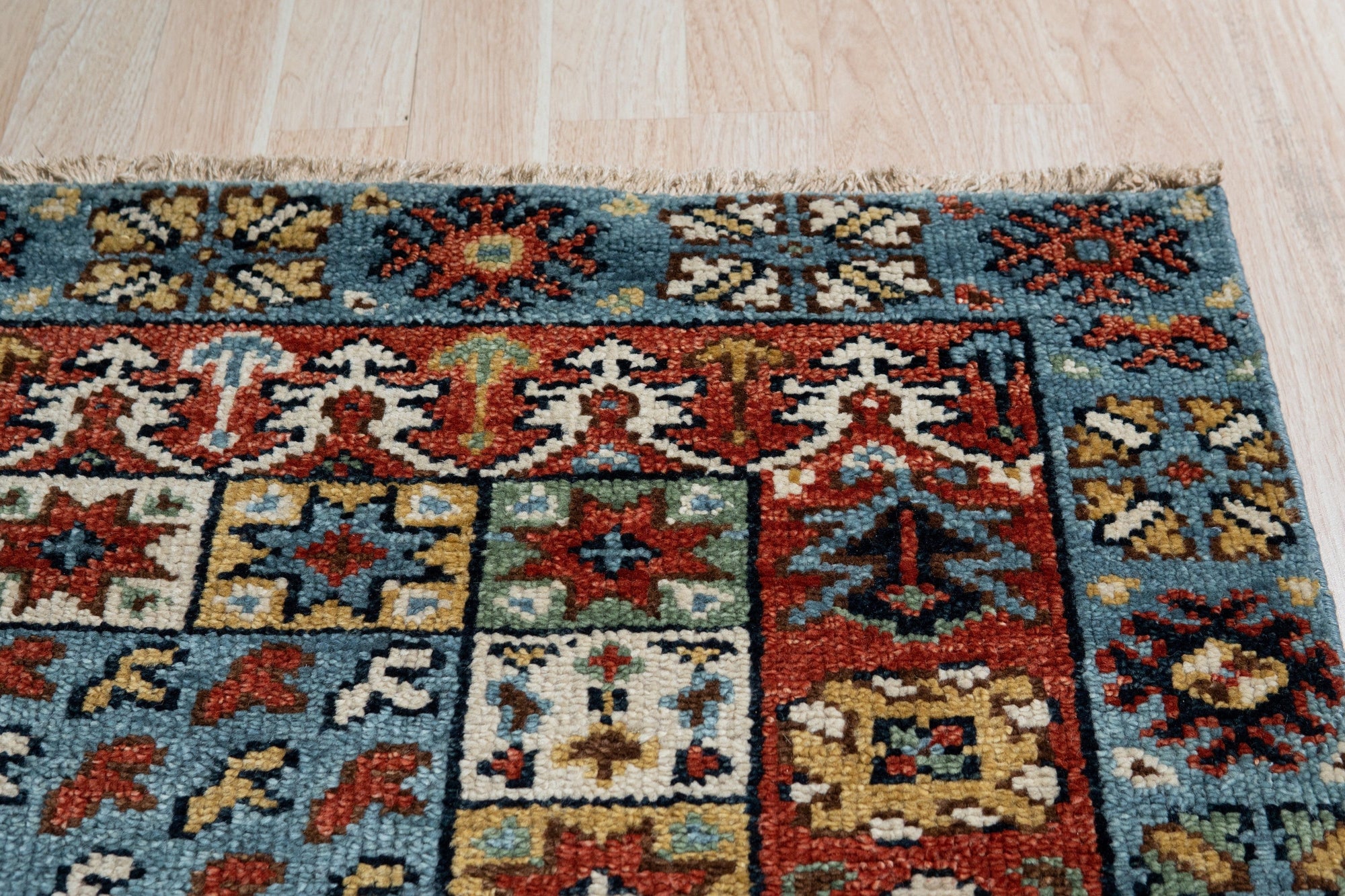 Mira Traditional Red Hand Knotted Wool Rug, a vibrant wool floor covering with intricate traditional motifs, lies flat in a well-lit space.