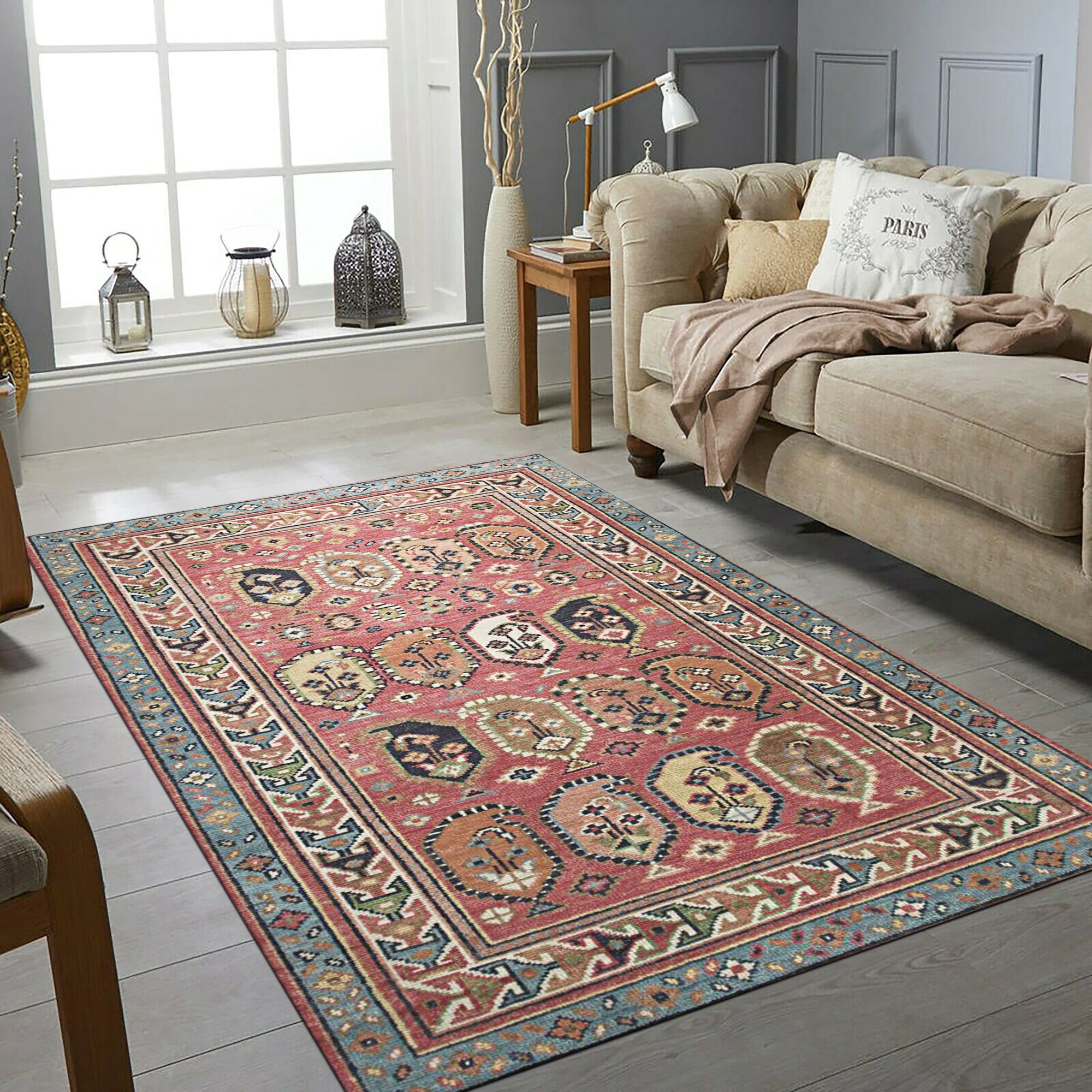 Kira Traditional Red Hand Knotted Wool Rug, displaying intricate floral and geometric motifs in vibrant reds, creams, and blues, filling a warm living space.