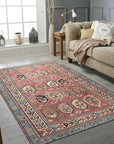 Kira Traditional Red Hand Knotted Wool Rug, displaying intricate floral and geometric motifs in vibrant reds, creams, and blues, filling a warm living space.