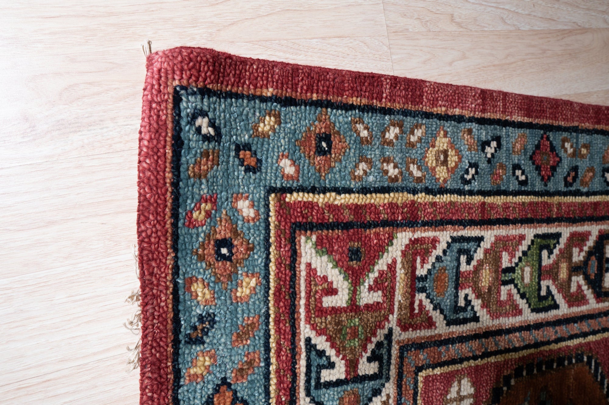 Kira Traditional Red Hand Knotted Wool Rug, vibrant reds and intricate traditional patterns adorn this hand-knotted wool rug, seen in a styled room setting.