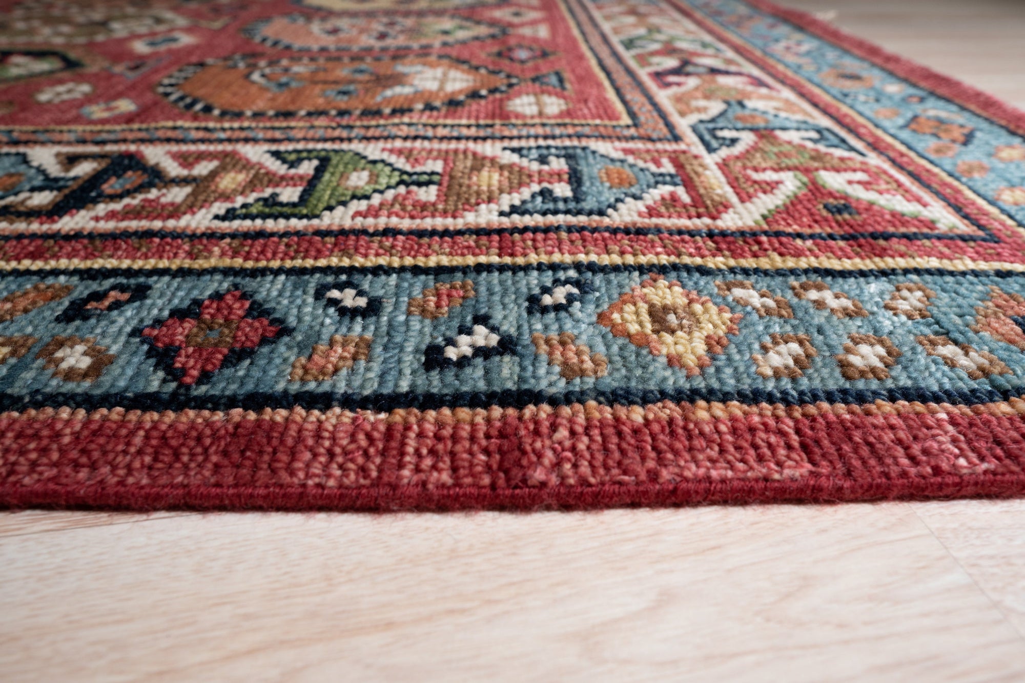Kira Traditional Red Hand Knotted Wool Rug displayed. Red and ivory tones define this hand-knotted wool rug, showcasing intricate traditional patterns.