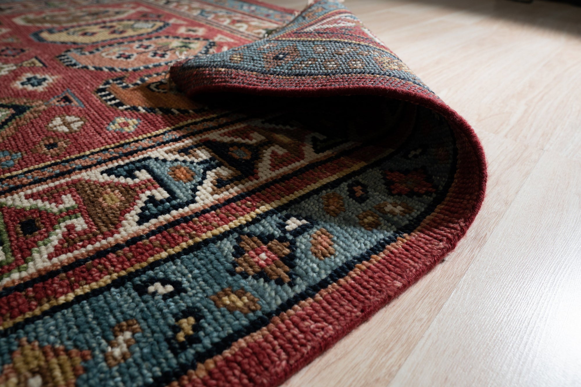 Kira Traditional Red Hand Knotted Wool Rug, vibrant reds and intricate patterns unfold across this hand-knotted wool rug, its classic design adding warmth to a softly lit room.