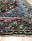 Vibrant Traditional Green Hand Knotted Wool Rug, exhibiting intricate floral patterns and geometric borders in shades of green, beige, and rust, seen in a well-lit room with hardwood floors, showcasing its rich texture and classic appeal.
