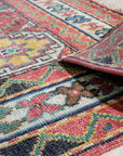 Lydia Kazak Brown Hand Knotted Wool Rug, its intricate geometric pattern in earthy browns and creams grounding a softly lit living room, showcasing its texture and hand-knotted construction.
