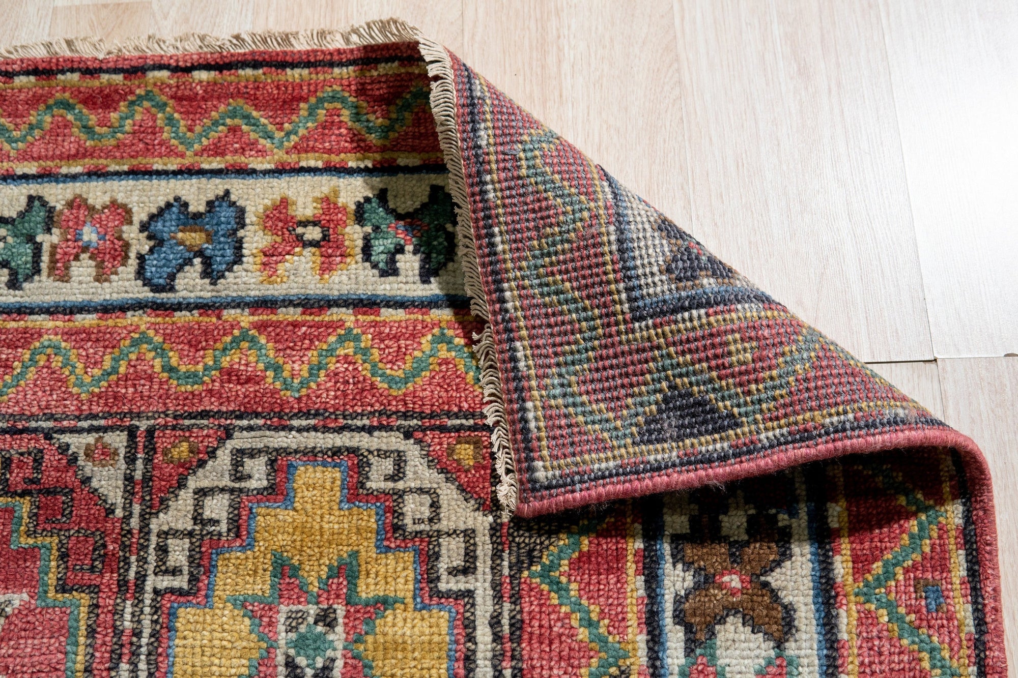 Lydia Kazak Brown Hand Knotted Wool Rug, its warm brown hues and intricate Kazak design grounding a warmly lit living space. Hand-knotted wool construction adds texture and depth.