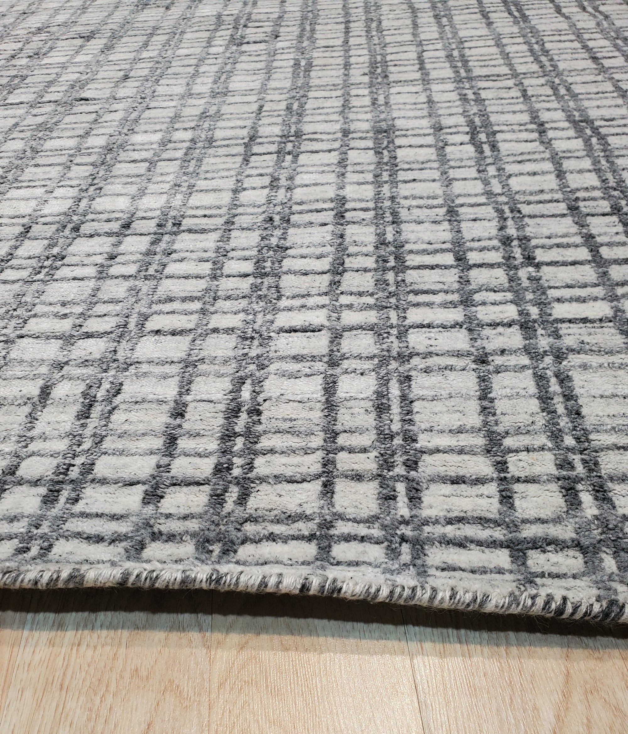 Given the image position is 4, here's the alt text:
 
 Sumptuous Jade Beige Handmade Wool & Viscose Rug, its subtle sheen highlighting intricate design details, rests on a dark wood floor, enhancing the rug's warm tones.