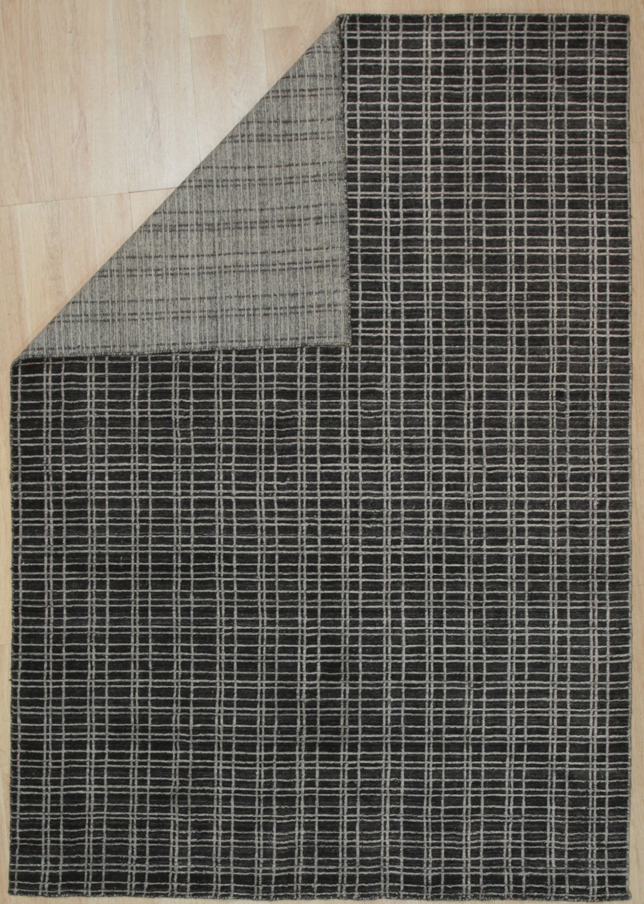 Sumptuous Jade Charcoal Handmade Wool & Viscose Rug, its deep charcoal background softly merging into jade green highlights, the plush wool and shimmering viscose fibers creating a luxurious texture underfoot, showcased in a warmly lit living room.