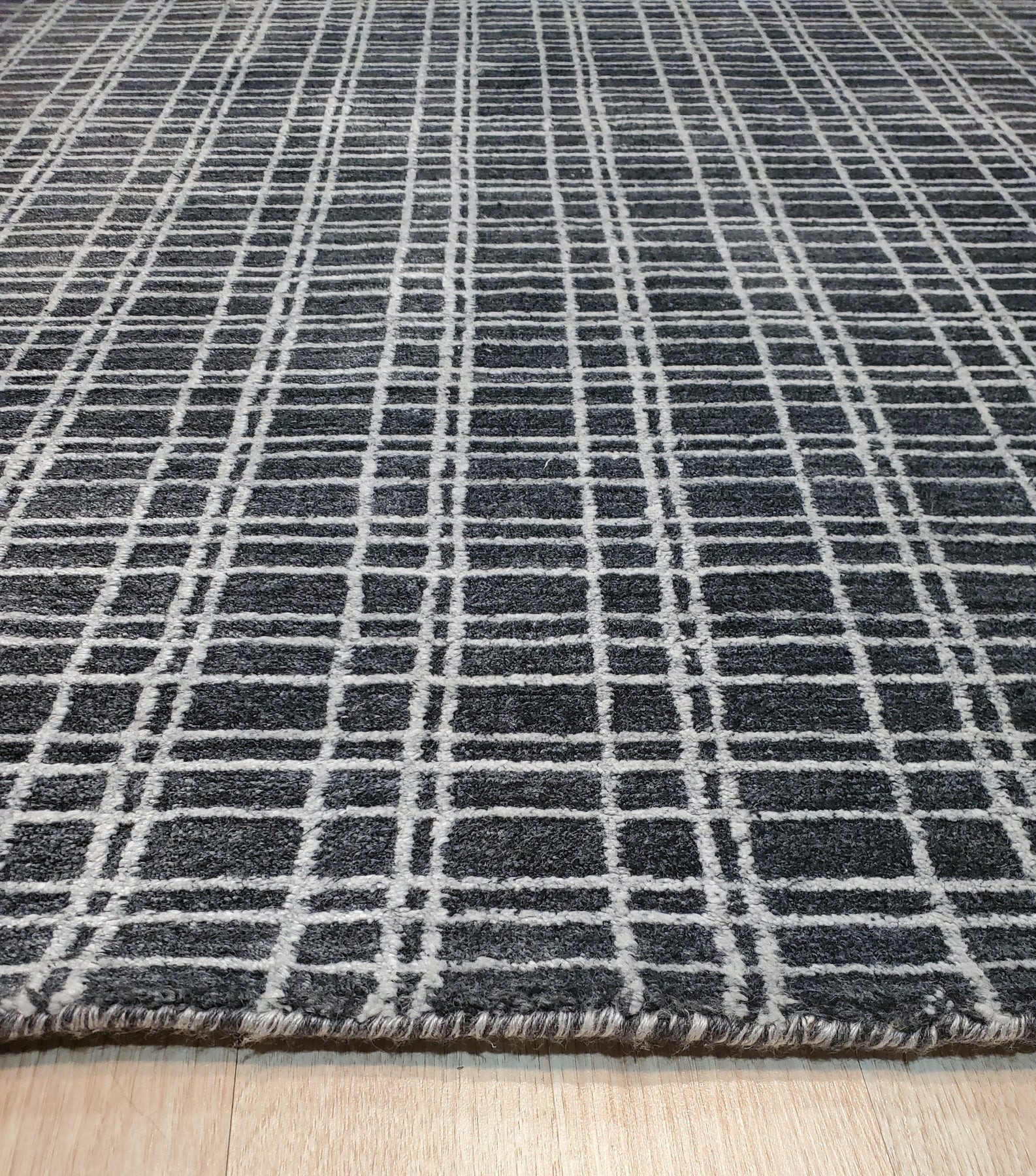 Sumptuous Jade Charcoal Handmade Wool & Viscose Rug displayed in a living room setting. Charcoal gray rug with subtle jade green highlights, showcasing a soft sheen from its wool and viscose construction.