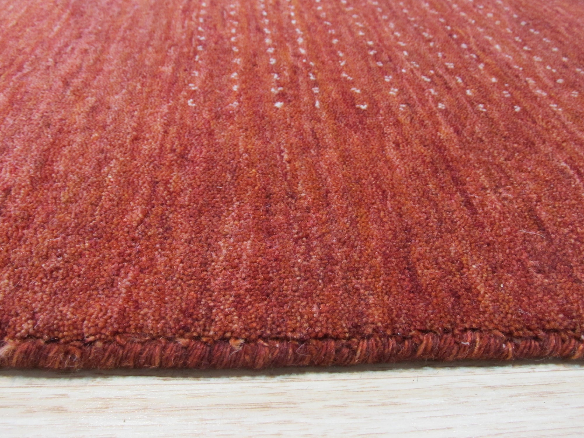 Willow Dazzling Red Handmade Wool Rug, showcasing its intricate pattern of geometric shapes and floral motifs in vibrant reds, creams, and subtle blues, adding warmth and sophistication to a contemporary living space.