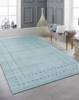 Jasmine Alluring Aqua Handmade Wool Rug, displaying a swirling, abstract pattern of varying aqua hues across its soft wool pile, presented in a bright, modern living room setting.