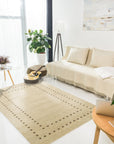 Jasmine Alluring Beige Handmade Wool Rug graces a warmly lit living room. Soft, alluring beige wool forms a captivating pattern, suggesting elegance underfoot. Sunlight highlights the rug’s intricate handmade construction, anchoring a cozy and inviting space.