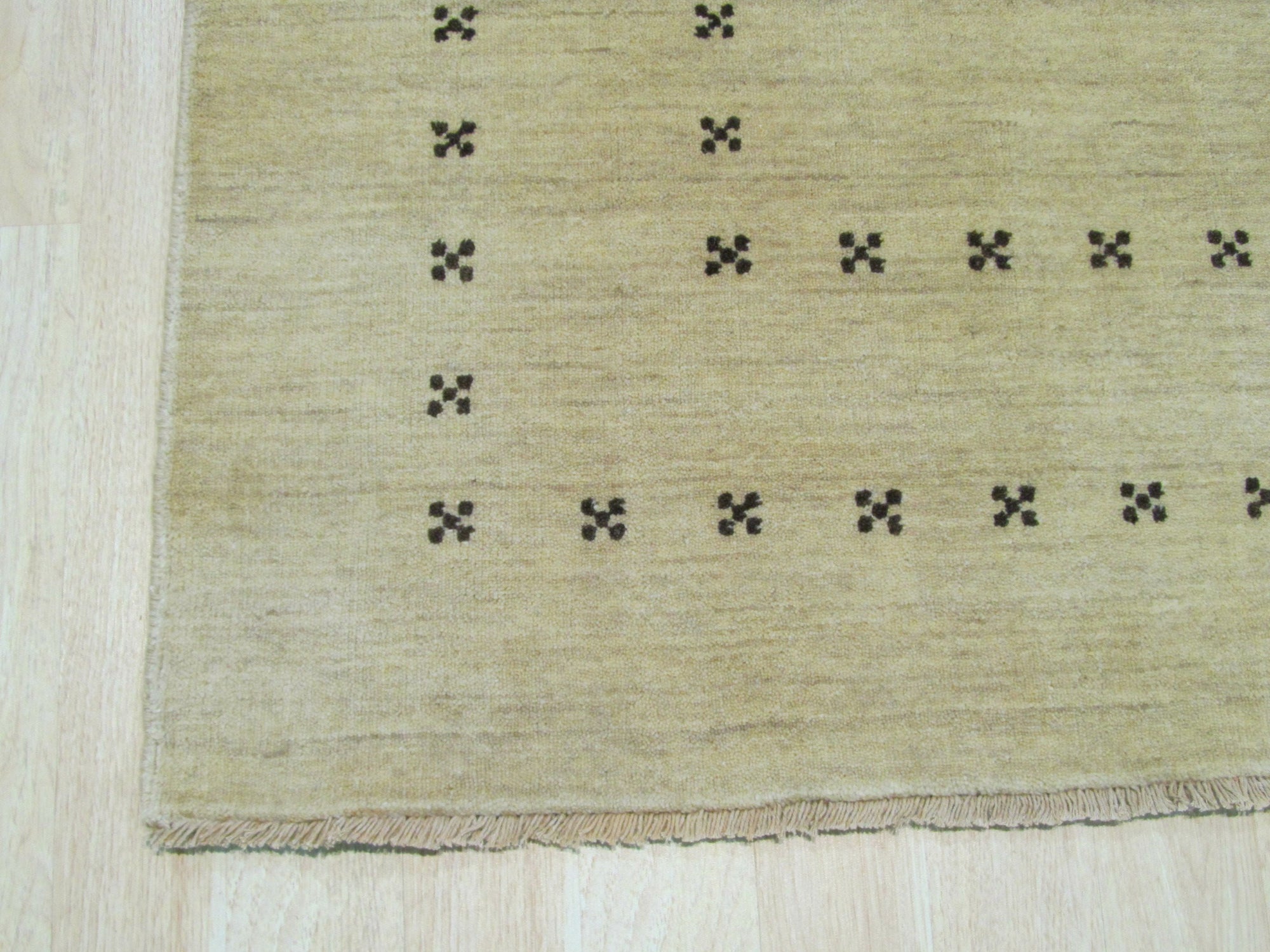 Jasmine Alluring Beige Handmade Wool Rug gracing a warmly lit living space; its soft beige tones and subtle textural weave complement the natural wood floors and minimalist decor, creating an inviting and serene atmosphere.