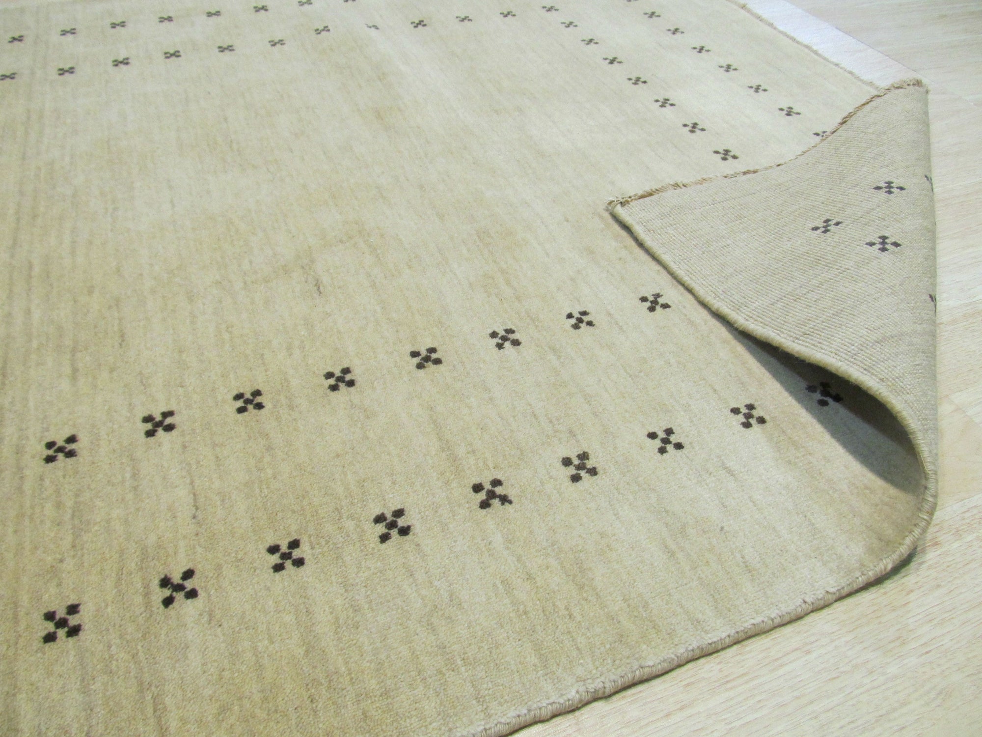 Jasmine Alluring Beige Handmade Wool Rug displayed, showcasing its soft, warm tones and handcrafted texture within a living room setting.