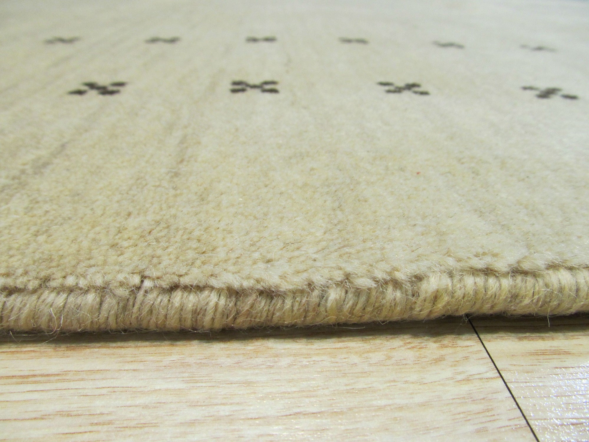 Jasmine Alluring Beige Handmade Wool Rug, a soft beige wool rug with subtle texture, complements a light wood floor and creates a warm, inviting atmosphere in a minimally decorated living space.