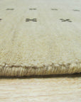 Jasmine Alluring Beige Handmade Wool Rug, a soft beige wool rug with subtle texture, complements a light wood floor and creates a warm, inviting atmosphere in a minimally decorated living space.