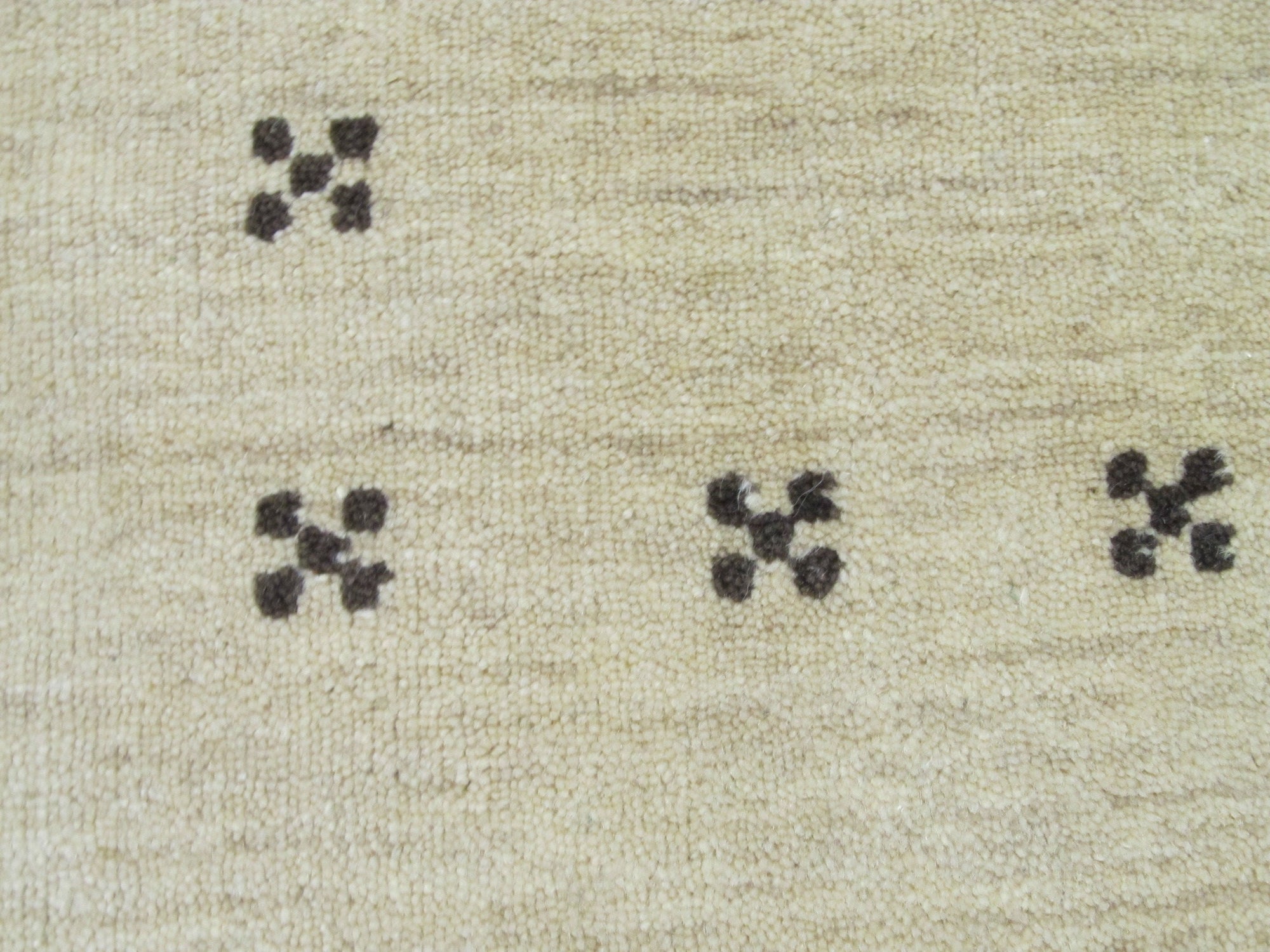 Jasmine Alluring Beige Handmade Wool Rug graces a softly lit living room. The hand-knotted wool pile displays subtle variations in beige tones, creating a warm, inviting atmosphere. Textured weave and understated elegance complement the room's decor.