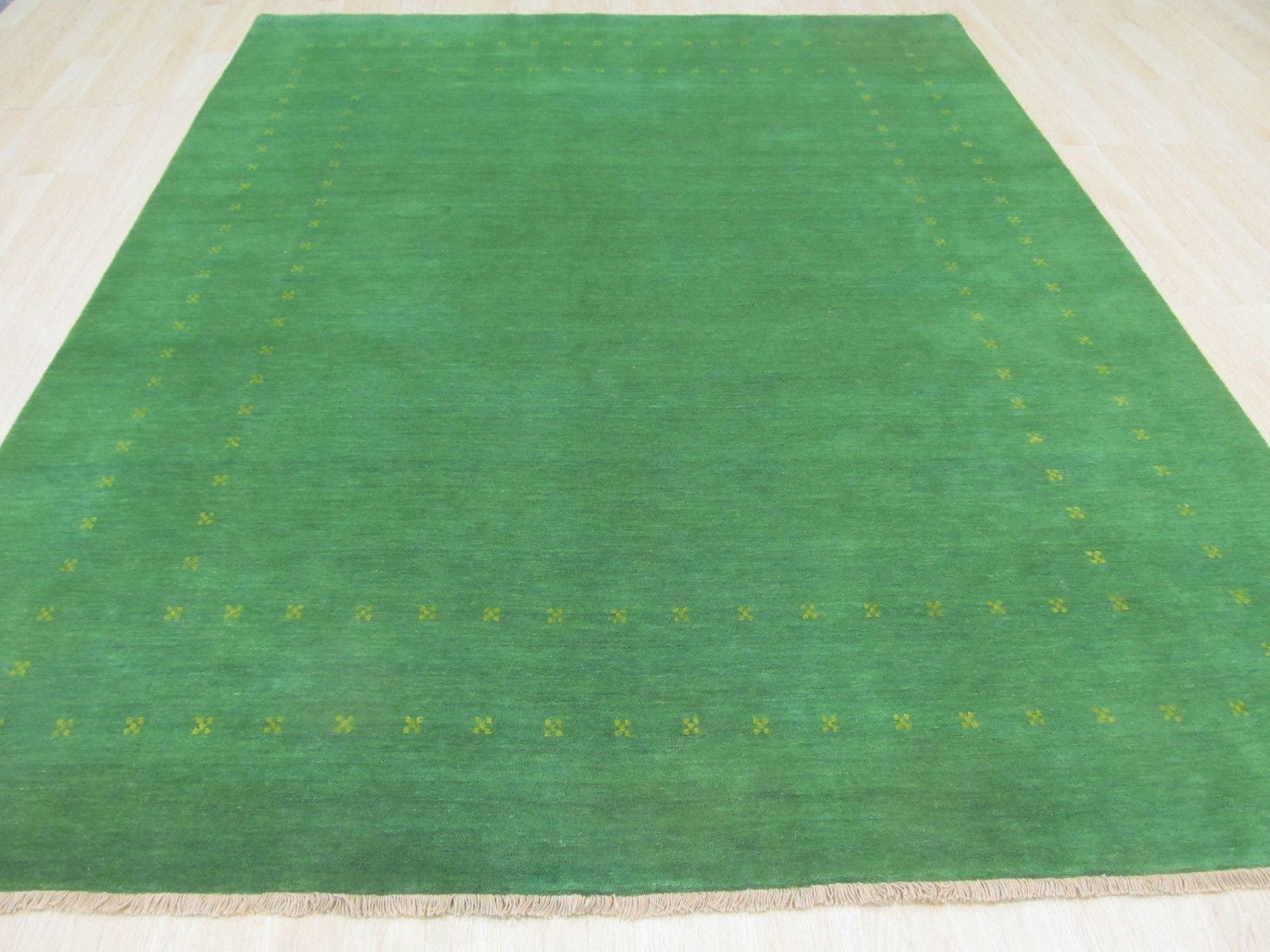 Jasmine Alluring Green Handmade Wool Rug, its verdant hues and handcrafted wool texture grounding a contemporary living space, sunlight dappling across its subtle, inviting pattern.