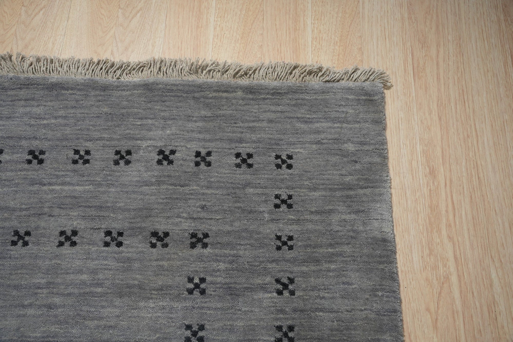 Jasmine Alluring Gray Handmade Wool Rug, showcasing its textured gray wool construction and subtle, elegant pattern in a well-lit living space setting.