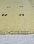 Jasmine Alluring Yellow Handmade Wool Rug, vibrant with sunny hues and intricate wool construction, lies elegantly on a light wood floor, its warmth radiating through the space.