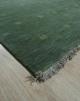 Laine Amara Green Handmade Wool Rug displayed on a light hardwood floor. Lush green tones blend seamlessly in this handcrafted wool rug, its subtle texture adding depth and warmth to the room.