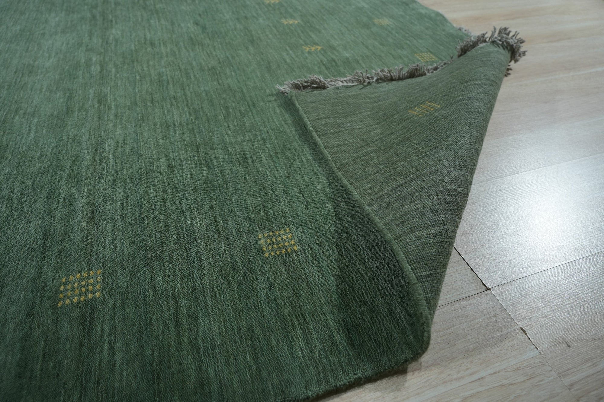Laine Amara Green Handmade Wool Rug, a lush expanse of green and neutral tones brings warmth to a light-filled living space. Wool construction offers a plush feel underfoot, while subtle design details complement the modern aesthetic.