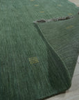 Laine Amara Green Handmade Wool Rug, a lush expanse of green and neutral tones brings warmth to a light-filled living space. Wool construction offers a plush feel underfoot, while subtle design details complement the modern aesthetic.