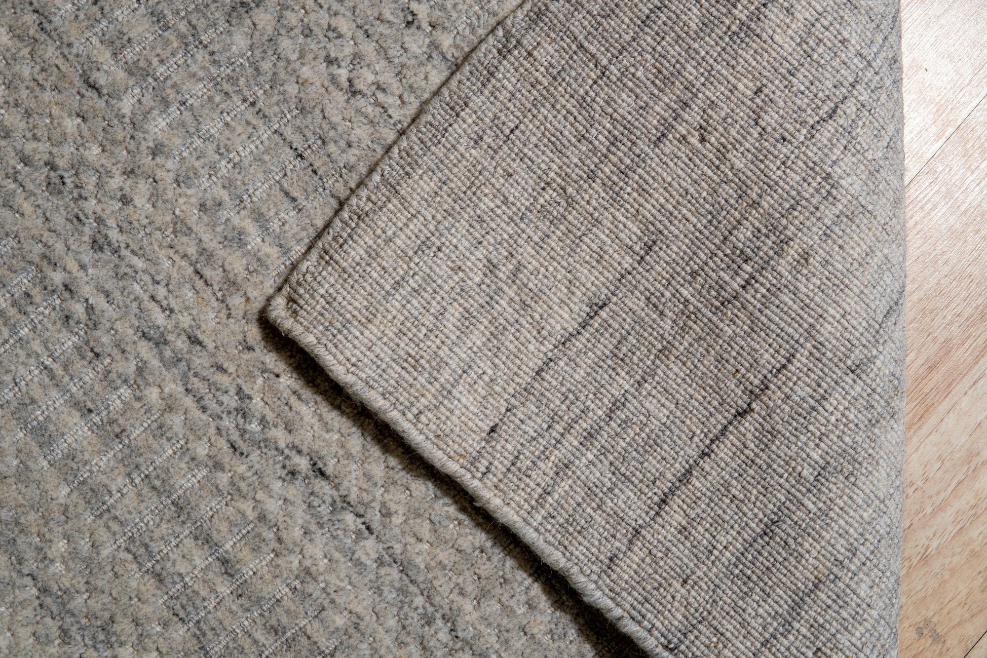 Celia Artistic Beige Handmade Wool Rug displayed in a living room setting; its neutral beige tones and subtle artistic pattern complementing the surrounding furniture and creating a warm, inviting atmosphere.