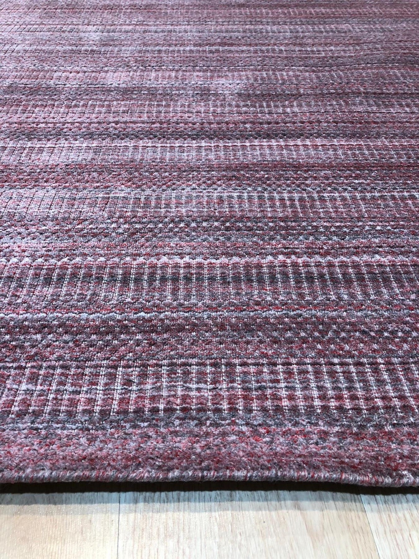 Radiant Elena Red Handmade Wool Rug, vibrant red hand-knotted wool rug with intricate floral and geometric patterns, partially visible within a brightly lit living room setting.