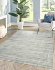 Tessa Xena Silver Handmade Wool Rug, seen in a bright, neutral living room setting, featuring a subtle geometric pattern in shades of silver and cream, hand-knotted wool construction providing a soft texture.
