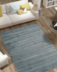 Para Elena Blue Handmade Wool Rug graces a living room, its intricate pattern of blues and creams anchoring the space. Woven wool construction brings warmth and texture to the scene, complementing the room's neutral palette.