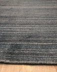 Para Elena Blue Handmade Wool Rug, showcasing intricate geometric patterns in shades of blue, cream, and terracotta. Hand-knotted wool rug displayed on a light hardwood floor, offering a warm and inviting feel. Soft light highlights the rug's textured surface and vibrant color variations.