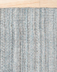 Para Elena Blue Handmade Wool Rug displayed in a warmly lit living space; its intricate, geometric pattern in shades of blue and cream complements the neutral decor and dark wood flooring, highlighting its hand-knotted wool construction and sophisticated design.
