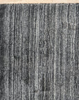 Penelope Nina Charcoal Handmade Wool Rug, showcasing intricate, textured patterns in varying shades of charcoal gray, filling a well-lit space with subtle depth and warmth.