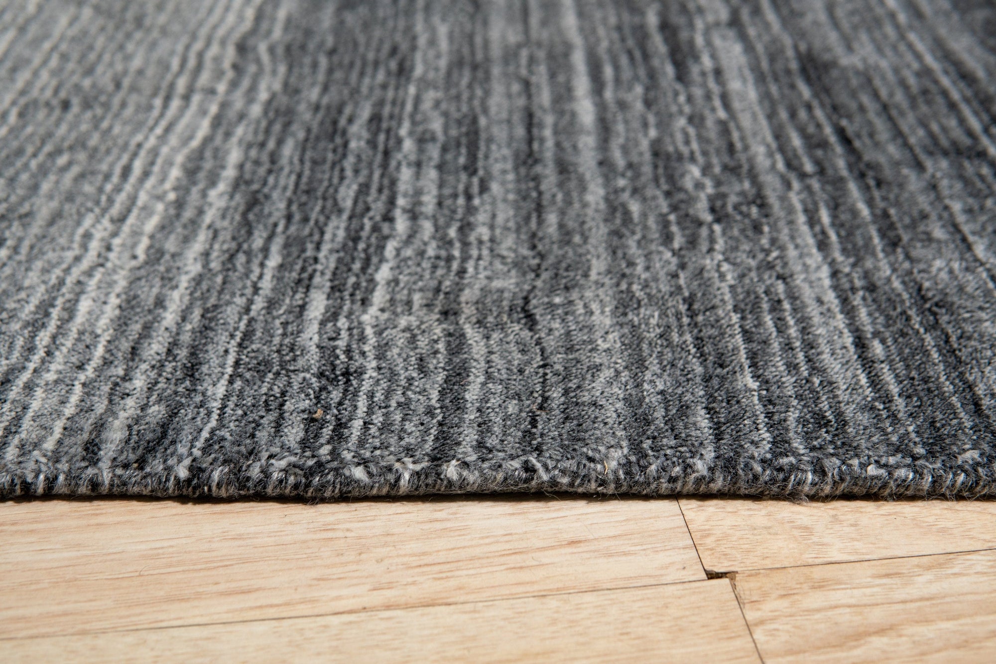 Penelope Nina Charcoal Handmade Wool Rug, featuring subtle patterns in varying shades of charcoal, creating depth and texture in a room setting.