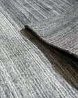 Penelope Nina Charcoal Handmade Wool Rug, showcasing subtle texture and varying shades of charcoal grey wool in a modern living room setting.