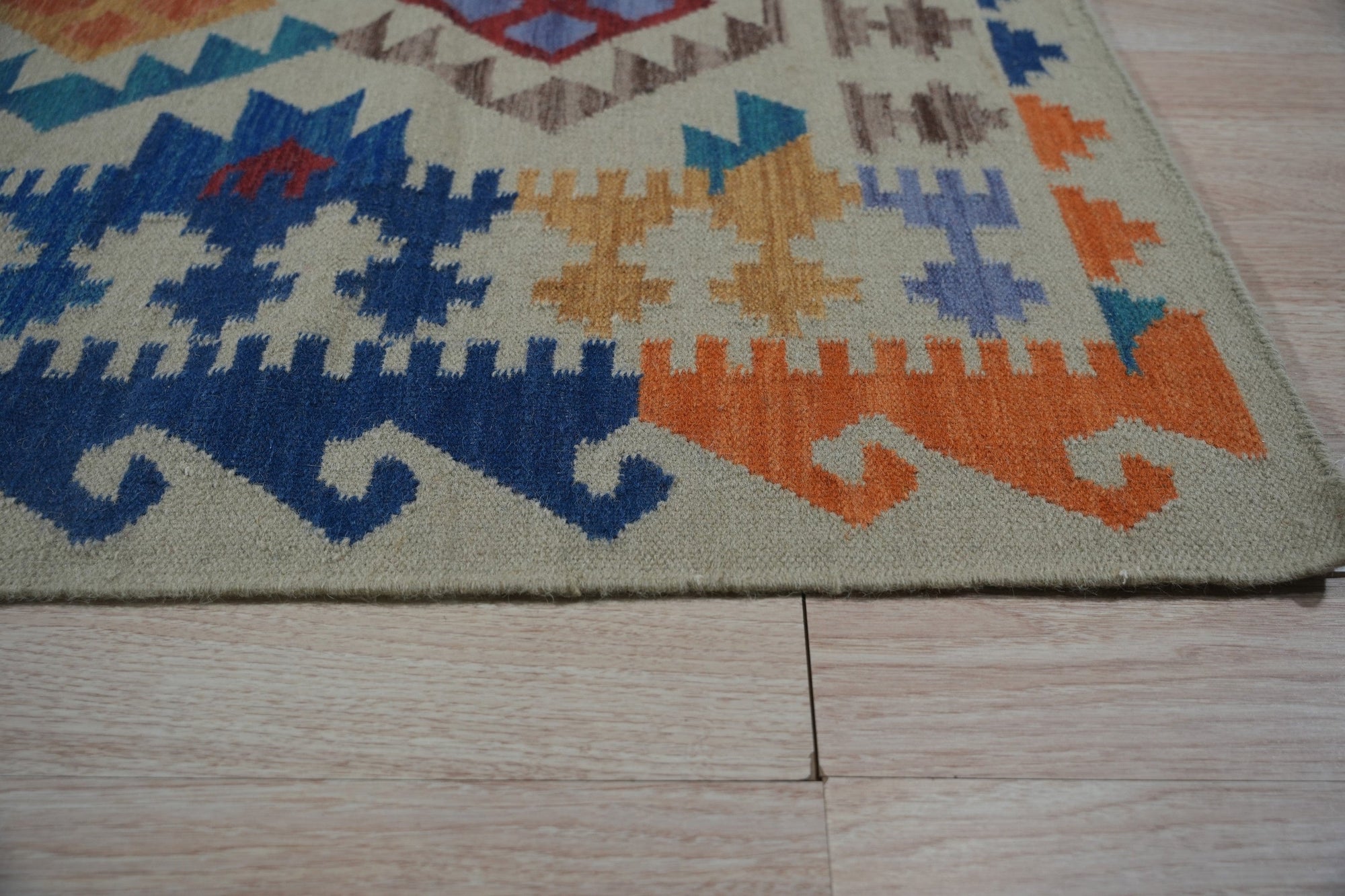 Nina Cassandra Multicolor Flatweave Wool Rug, its vibrant threads creating a dynamic geometric pattern. Woven wool flatweave displays a kaleidoscope of colors in this modern setting.