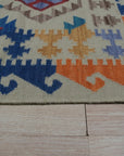 Nina Cassandra Multicolor Flatweave Wool Rug, its vibrant threads creating a dynamic geometric pattern. Woven wool flatweave displays a kaleidoscope of colors in this modern setting.