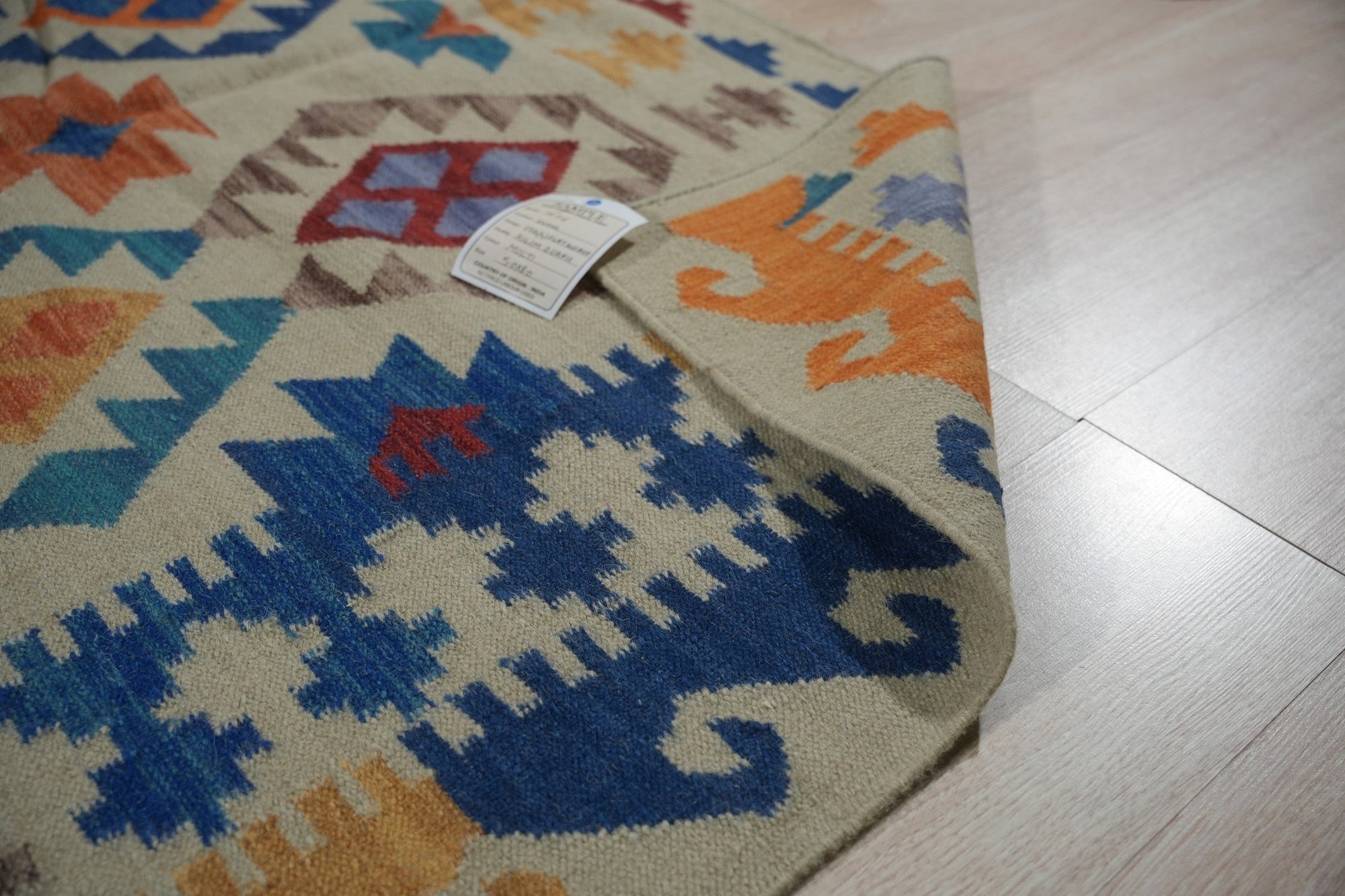 Nina Cassandra Multicolor Flatweave Wool Rug, vibrant hues dance across a flatweave wool texture, adding bohemian flair to a light-filled room with modern furniture.