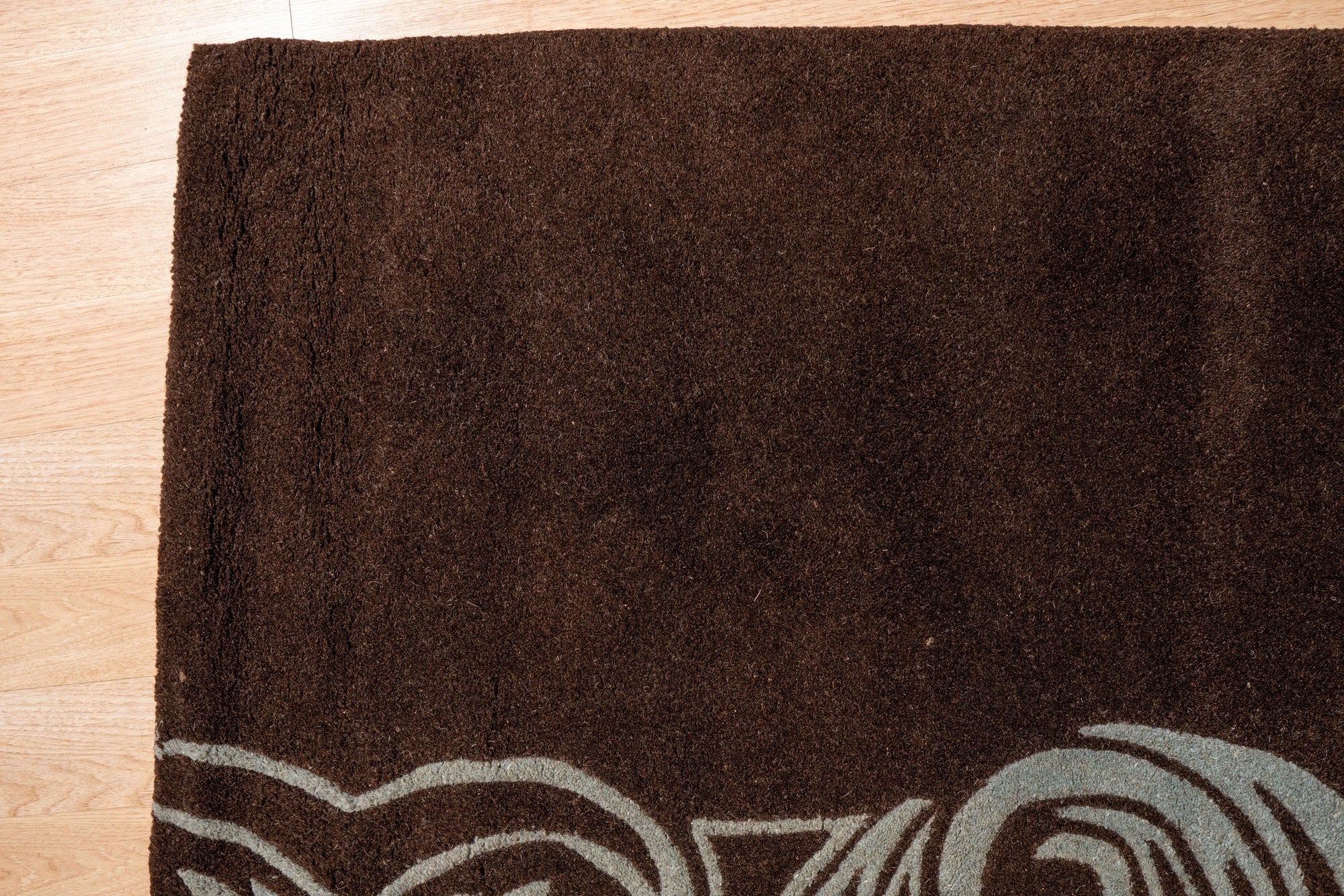 Yara Para Brown Hand Tufted Wool Rug anchoring a living room, its earthy brown tones complementing a cream-colored sofa and wooden coffee table, showcasing inviting texture and warmth.